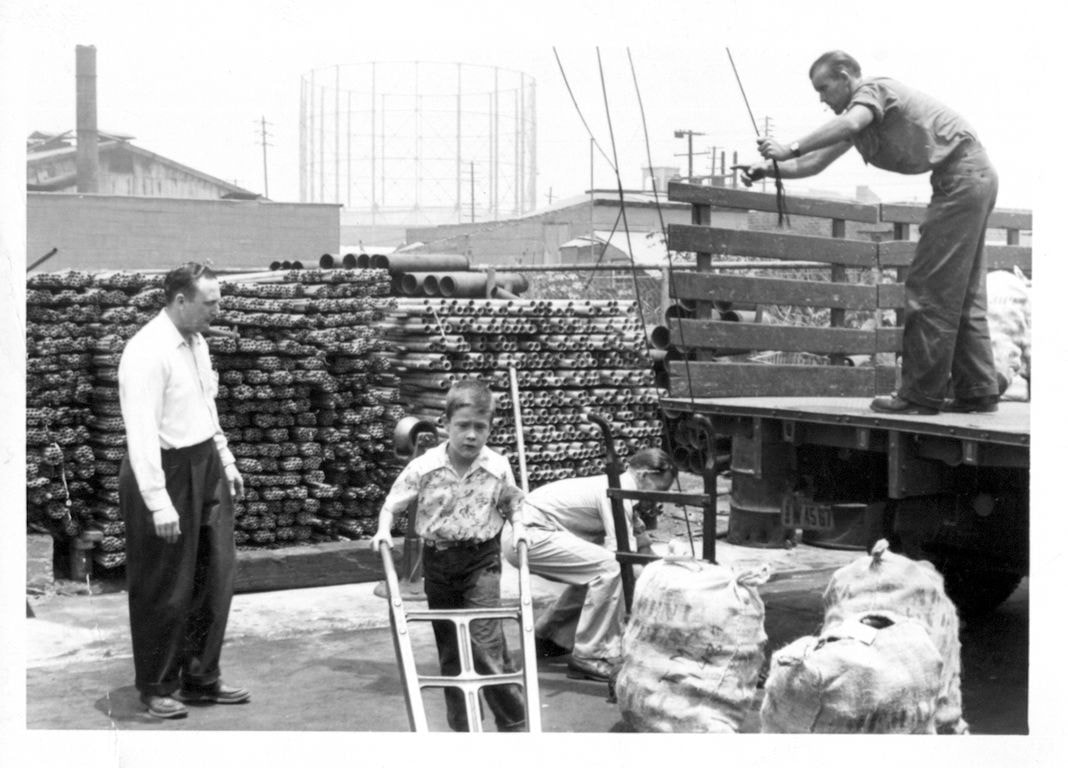 Historical black-and-white photo of E.A. Gray workers loading pipe at the yard