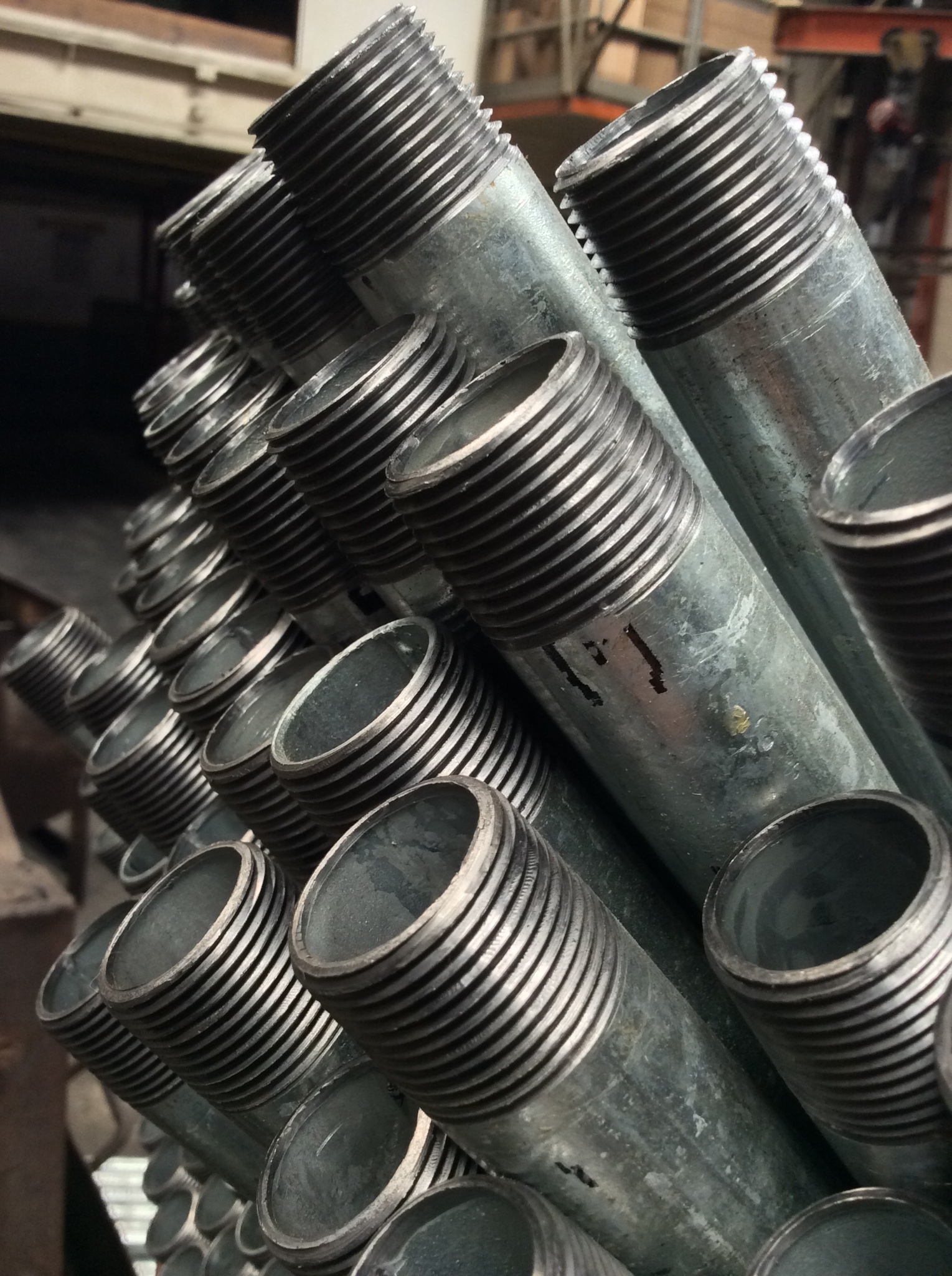 Galvanized steel pipe nipples stacked showing threaded ends
