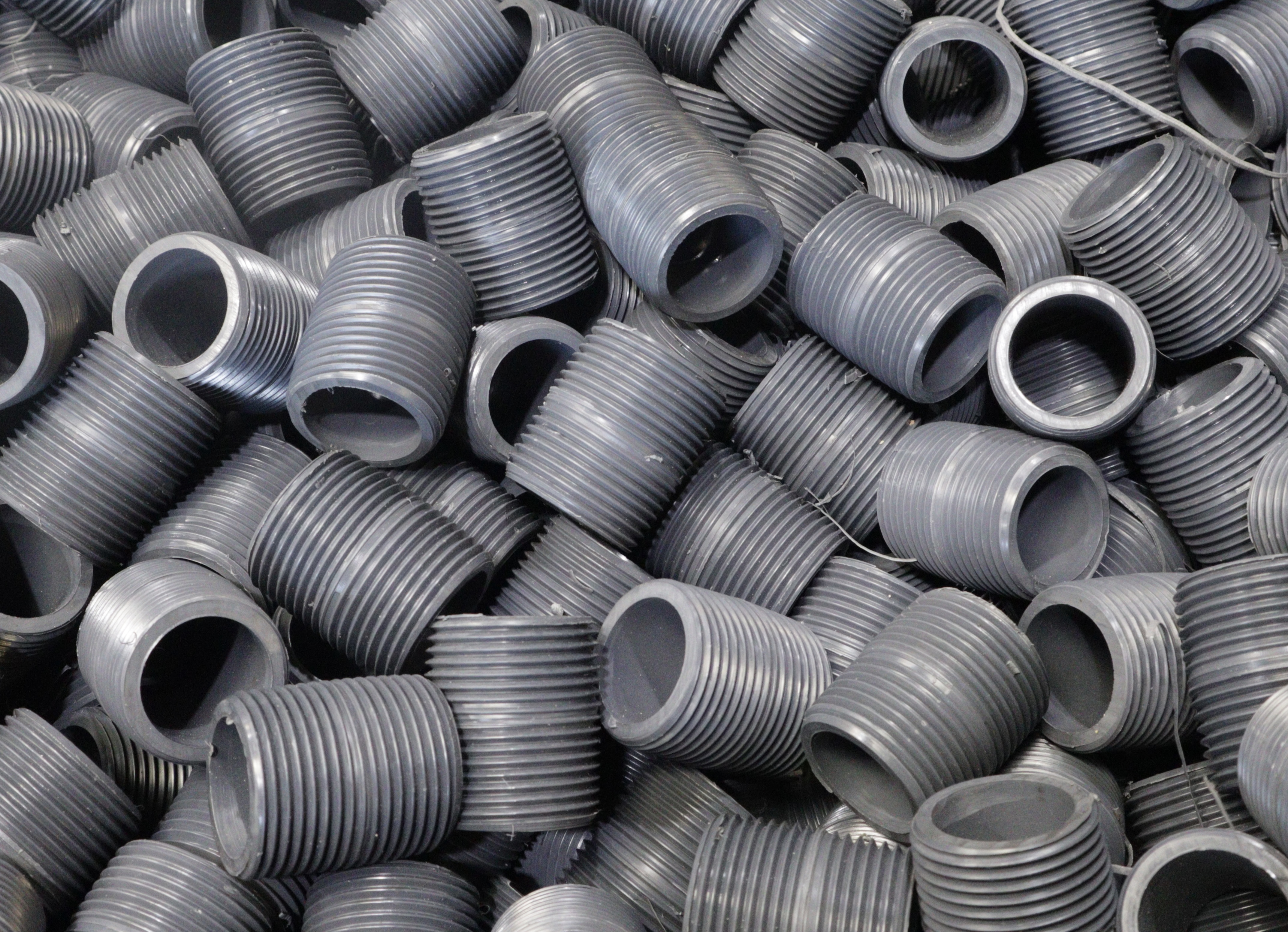 Large pile of gray PVC close nipples showing precision molded NPT threads